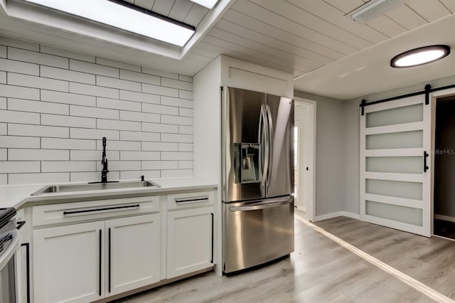 7031 Magnolia Valley Dr, New Port Richey, FL 34653 - kitchen featuring stainless steel fridge with ice dispenser, a barn door, decorative backsplash, stove, and light wood-type flooring