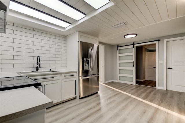 7031 Magnolia Valley Dr, New Port Richey, FL 34653 - kitchen featuring stainless steel refrigerator with ice dispenser, a barn door, backsplash, white cabinetry, and light countertops
