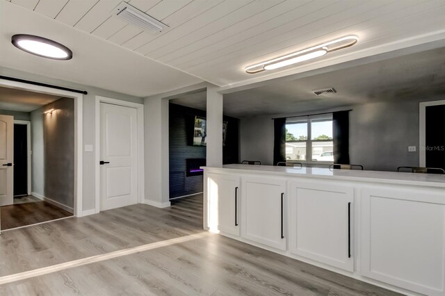 7031 Magnolia Valley Dr, New Port Richey, FL 34653 - kitchen featuring a warm lit fireplace, light wood-type flooring, and white cabinets