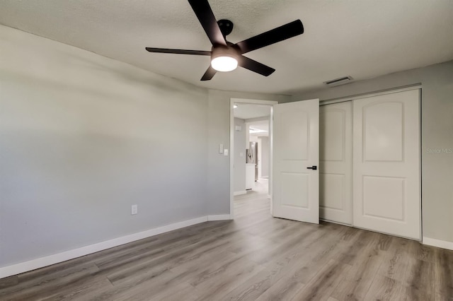 7031 Magnolia Valley Dr, New Port Richey, FL 34653 - unfurnished bedroom featuring light wood-style flooring, a closet, a ceiling fan, and a textured ceiling