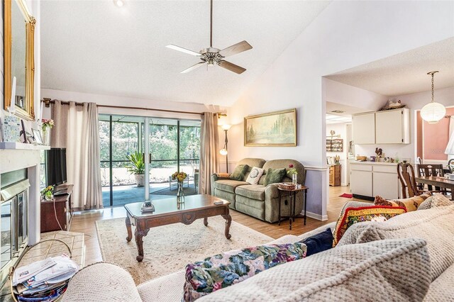 3335 Foxridge Cir, Tampa, FL 33618 - living room featuring light wood finished floors, ceiling fan, high vaulted ceiling, and a glass covered fireplace