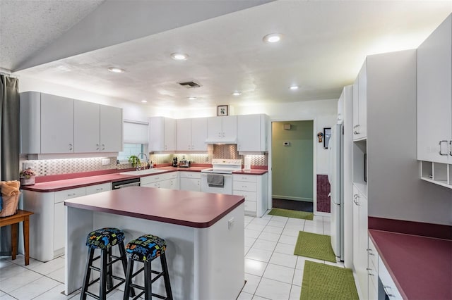 1810 Orange Hill Dr, Brandon, FL 33510 - kitchen with white appliances, a breakfast bar, light tile patterned flooring, decorative backsplash, and recessed lighting