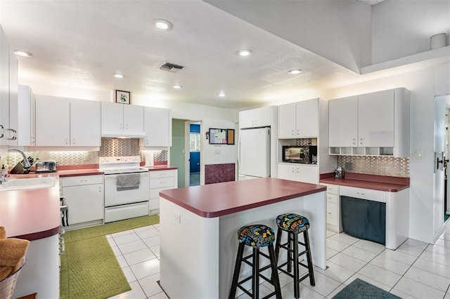 1810 Orange Hill Dr, Brandon, FL 33510 - kitchen with white appliances, backsplash, light tile patterned flooring, a kitchen bar, and recessed lighting