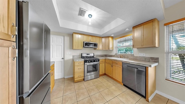 11460 Park Blvd, Seminole, FL 33772 - kitchen with stainless steel appliances, a textured ceiling, a raised ceiling, light brown cabinets, and light countertops