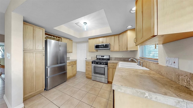 11460 Park Blvd, Seminole, FL 33772 - kitchen with appliances with stainless steel finishes, light brown cabinetry, a raised ceiling, light countertops, and light tile patterned floors