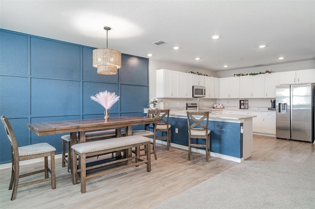 1518 Louise Ave, Auburndale, FL 33823 - kitchen featuring stainless steel appliances, a decorative wall, light wood finished floors, white cabinets, and light countertops