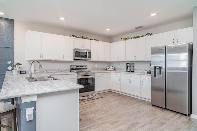 1518 Louise Ave, Auburndale, FL 33823 - kitchen with stainless steel appliances, a peninsula, white cabinets, light wood finished floors, and recessed lighting