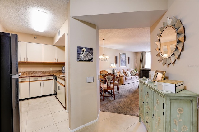 2333 Feather Sound Dr Unit A409, Clearwater, FL 33762 - kitchen with a textured ceiling, freestanding refrigerator, white cabinetry, light colored carpet, and a chandelier