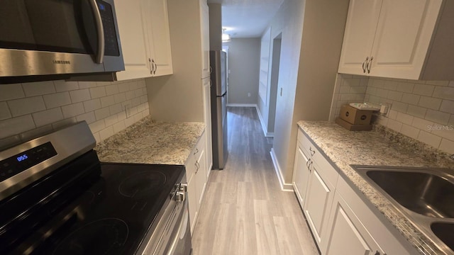 1514 Crest Ave, Leesburg, FL 34748 - kitchen with stainless steel appliances, light wood-style floors, backsplash, and white cabinetry