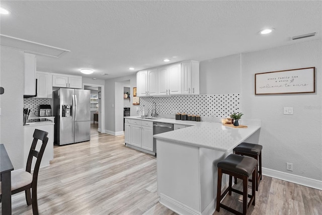 4460 67th St N, Saint Petersburg, FL 33709 - kitchen with appliances with stainless steel finishes, a peninsula, tasteful backsplash, a kitchen bar, and recessed lighting