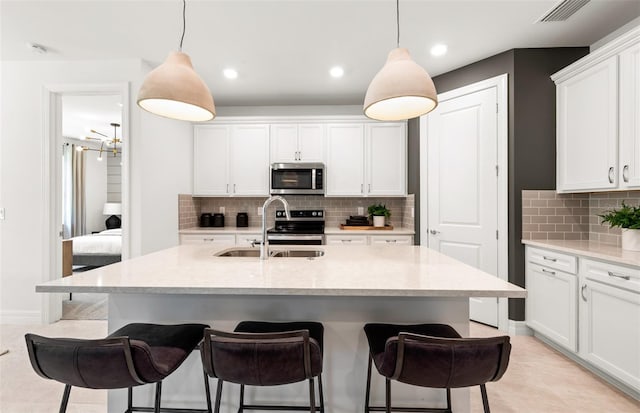 5719 Silverside Pine Ct, Lakewood Ranch, FL 34211 - kitchen with appliances with stainless steel finishes, a kitchen bar, backsplash, white cabinets, and decorative light fixtures