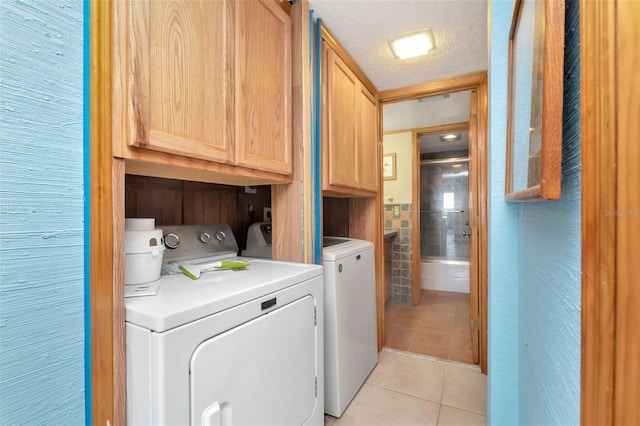 7893 Sailboat Key Blvd S Unit 304, South Pasadena, FL 33707 - laundry room with cabinet space, washer and clothes dryer, light tile patterned flooring, and a textured ceiling