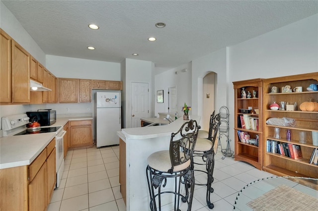 7603 Wood Violet Dr, Gibsonton, FL 33534 - kitchen with white appliances, under cabinet range hood, arched walkways, light countertops, and a kitchen breakfast bar