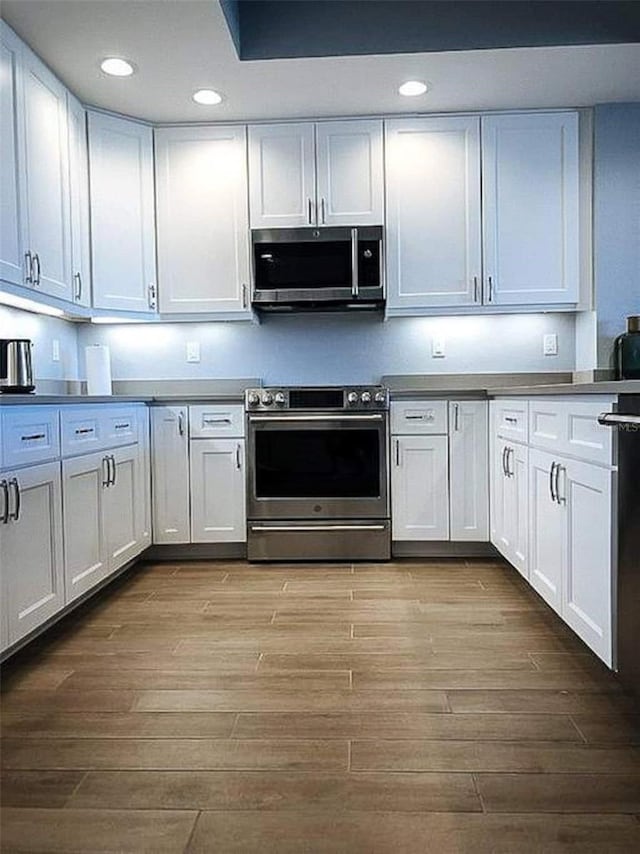 706 Bayway Blvd Unit 502, Clearwater Beach, FL 33767 - kitchen featuring stainless steel appliances, dark wood finished floors, recessed lighting, and white cabinets