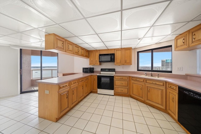 1340 Gulf Blvd Unit 12A, Clearwater Beach, FL 33767 - kitchen with black appliances, plenty of natural light, a peninsula, and light countertops