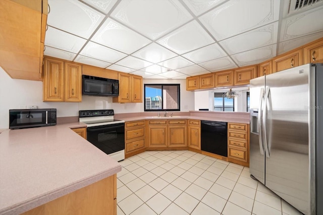 1340 Gulf Blvd Unit 12A, Clearwater Beach, FL 33767 - kitchen with black appliances, light countertops, a peninsula, and light tile patterned flooring