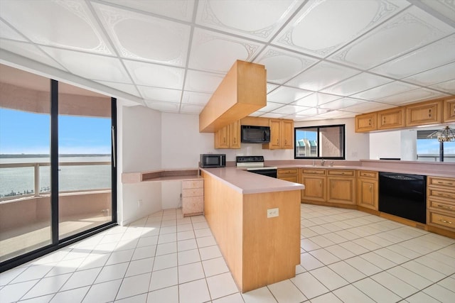 1340 Gulf Blvd Unit 12A, Clearwater Beach, FL 33767 - kitchen featuring black appliances, a peninsula, light countertops, light tile patterned floors, and a water view