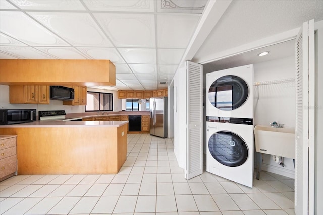1340 Gulf Blvd Unit 12A, Clearwater Beach, FL 33767 - kitchen featuring black appliances, stacked washing machine and dryer, a peninsula, light countertops, and recessed lighting