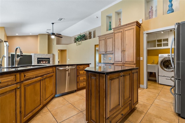 1046 Middlesex Dr, New Port Richey, FL 34655 - kitchen with stainless steel appliances, ceiling fan, washer / clothes dryer, brown cabinetry, and light tile patterned floors
