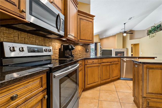 1046 Middlesex Dr, New Port Richey, FL 34655 - kitchen with appliances with stainless steel finishes, brown cabinets, ceiling fan, backsplash, and vaulted ceiling