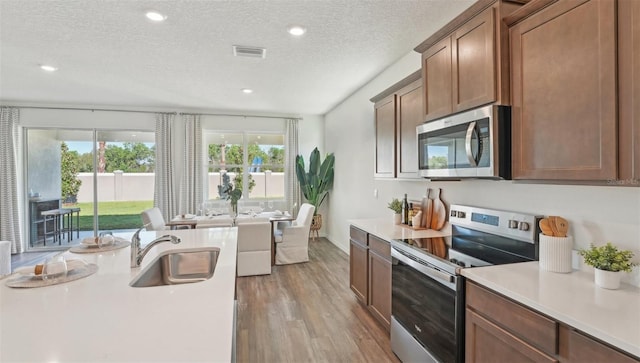 7803 Wheat Stone Dr, Zephyrhills, FL 33540 - kitchen with appliances with stainless steel finishes, wood finished floors, light countertops, a textured ceiling, and recessed lighting