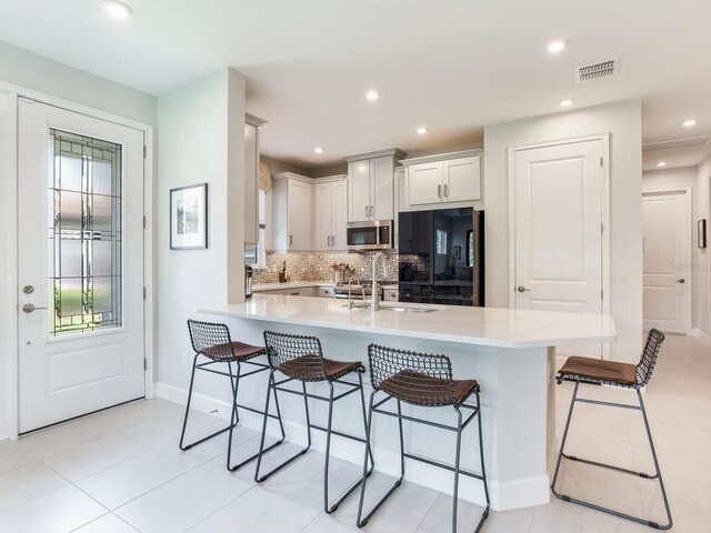 5317 Rushmere Ct, Palmetto, FL 34221 - kitchen with stainless steel microwave, refrigerator, a breakfast bar, backsplash, and recessed lighting