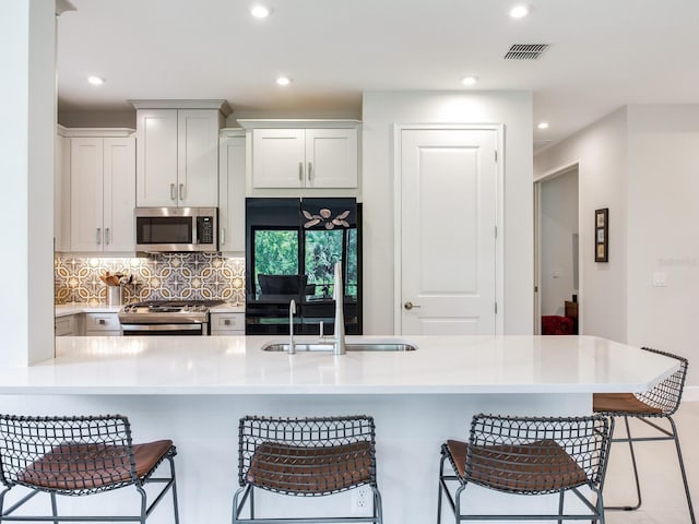 5317 Rushmere Ct, Palmetto, FL 34221 - kitchen featuring appliances with stainless steel finishes, a kitchen bar, backsplash, recessed lighting, and light countertops