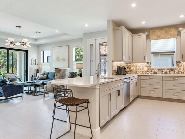 5317 Rushmere Ct, Palmetto, FL 34221 - kitchen with a chandelier, a peninsula, stainless steel dishwasher, light countertops, and decorative backsplash