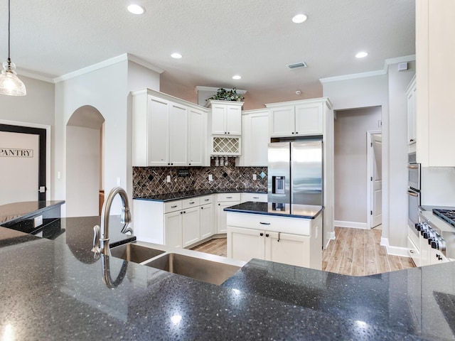 3503 Graycliff Ln, Brandon, FL 33511 - kitchen featuring stainless steel appliances, ornamental molding, decorative backsplash, white cabinets, and arched walkways