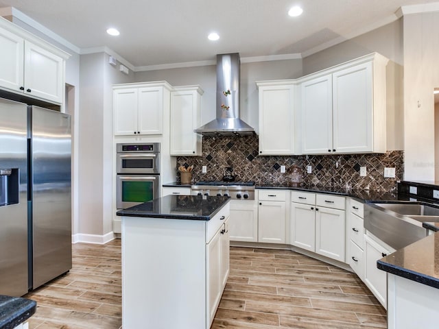 3503 Graycliff Ln, Brandon, FL 33511 - kitchen featuring appliances with stainless steel finishes, wall chimney range hood, crown molding, light wood-type flooring, and white cabinets