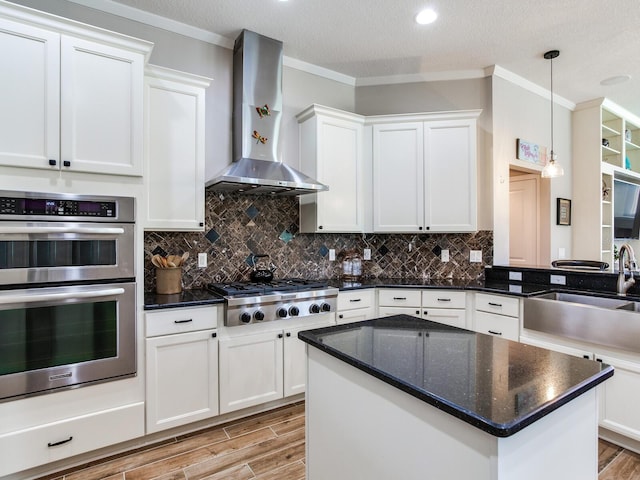 3503 Graycliff Ln, Brandon, FL 33511 - kitchen featuring wall chimney range hood, stainless steel appliances, light wood-type flooring, crown molding, and white cabinetry