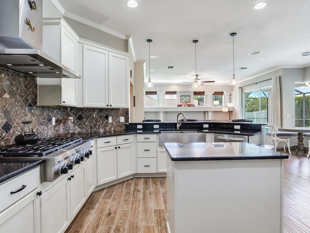 3503 Graycliff Ln, Brandon, FL 33511 - kitchen with wall chimney exhaust hood, stainless steel appliances, ceiling fan, light wood-type flooring, and white cabinets