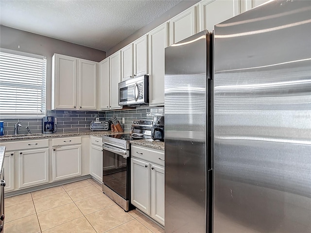 18339 Fish Loop, Land O Lakes, FL 34638 - kitchen featuring appliances with stainless steel finishes, backsplash, stone countertops, light tile patterned floors, and white cabinetry