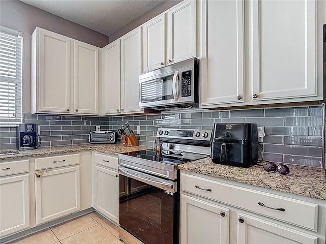 18339 Fish Loop, Land O Lakes, FL 34638 - kitchen with appliances with stainless steel finishes, backsplash, white cabinetry, light tile patterned floors, and light stone countertops