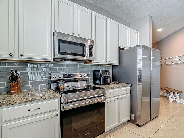 18339 Fish Loop, Land O Lakes, FL 34638 - kitchen with appliances with stainless steel finishes, light tile patterned flooring, decorative backsplash, and a textured ceiling
