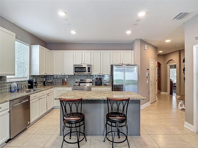18339 Fish Loop, Land O Lakes, FL 34638 - kitchen featuring stainless steel appliances, arched walkways, a kitchen breakfast bar, backsplash, and recessed lighting