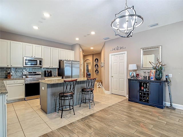 18339 Fish Loop, Land O Lakes, FL 34638 - kitchen with appliances with stainless steel finishes, a chandelier, backsplash, a kitchen island, and wood tiled floors
