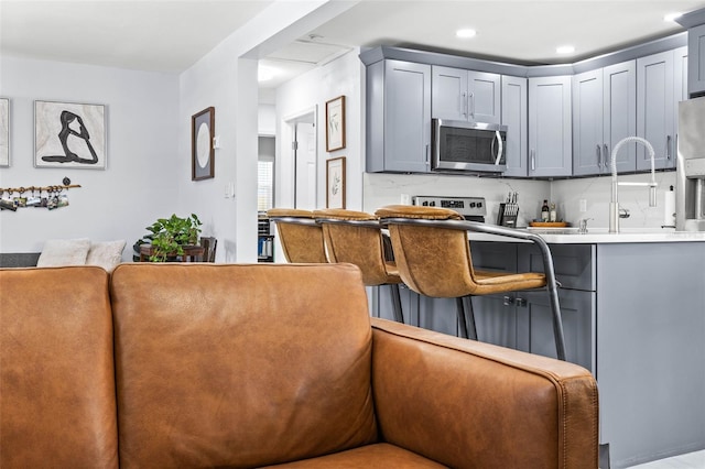 1406 Nebraska Ave, Palm Harbor, FL 34683 - kitchen featuring stainless steel microwave, gray cabinetry, light countertops, and a kitchen breakfast bar