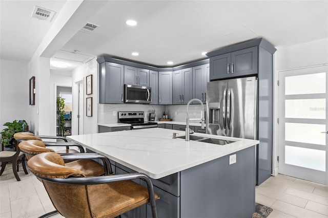 1406 Nebraska Ave, Palm Harbor, FL 34683 - kitchen with stainless steel appliances, light stone countertops, a center island with sink, gray cabinets, and recessed lighting