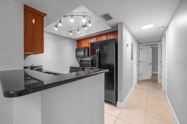 720 Lyndhurst St Unit 1101, Dunedin, FL 34698 - kitchen with black appliances, light tile patterned floors, a peninsula, a textured wall, and dark stone countertops