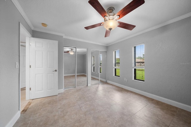 720 Lyndhurst St Unit 1101, Dunedin, FL 34698 - unfurnished bedroom with two closets, ornamental molding, light tile patterned floors, and a ceiling fan