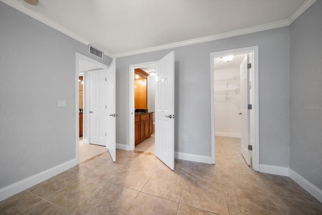 720 Lyndhurst St Unit 1101, Dunedin, FL 34698 - unfurnished bedroom with crown molding, light tile patterned flooring, a spacious closet, ensuite bath, and a closet
