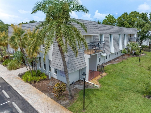 720 Lyndhurst St Unit 1101, Dunedin, FL 34698 - view of property exterior featuring a yard, stucco siding, a balcony, and uncovered parking