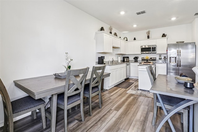 6235 Bucket Ct, Gibsonton, FL 33534 - kitchen with stainless steel appliances, wood finished floors, white cabinetry, recessed lighting, and light stone counters