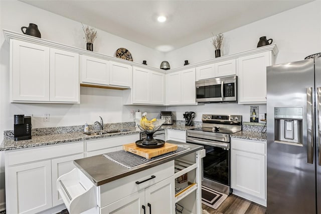 6235 Bucket Ct, Gibsonton, FL 33534 - kitchen with appliances with stainless steel finishes, white cabinetry, dark wood finished floors, light stone counters, and a kitchen island