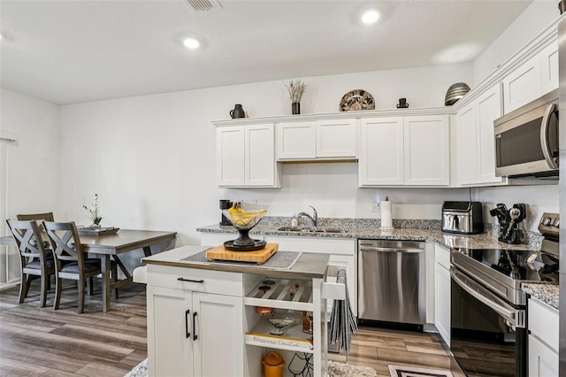 6235 Bucket Ct, Gibsonton, FL 33534 - kitchen featuring stainless steel appliances, white cabinets, light wood finished floors, light stone counters, and recessed lighting