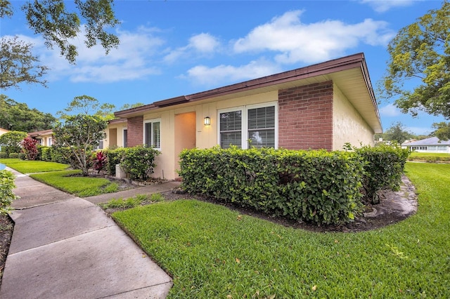 900 Maclaren Dr N Unit D, Palm Harbor, FL 34684 - view of front of home featuring a front lawn, brick siding, and stucco siding