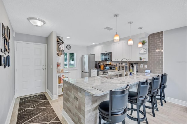 900 Maclaren Dr N Unit D, Palm Harbor, FL 34684 - kitchen featuring black microwave, range with electric cooktop, freestanding refrigerator, a peninsula, and white cabinetry