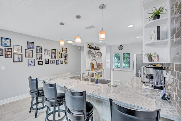 900 Maclaren Dr N Unit D, Palm Harbor, FL 34684 - kitchen with a peninsula, open shelves, recessed lighting, a kitchen breakfast bar, and decorative light fixtures