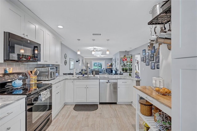 900 Maclaren Dr N Unit D, Palm Harbor, FL 34684 - kitchen with stainless steel appliances, a peninsula, light wood-type flooring, white cabinetry, and recessed lighting